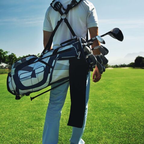 Golf man walking with shoulder bag on course in fairway