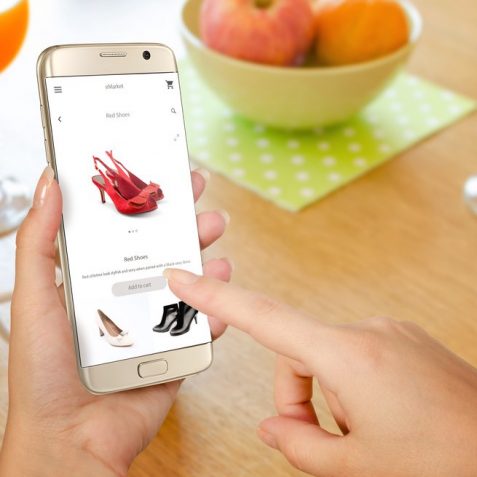 Online shopping with smart phone. Isolated phone in woman hand. Buying women shoes on online store.